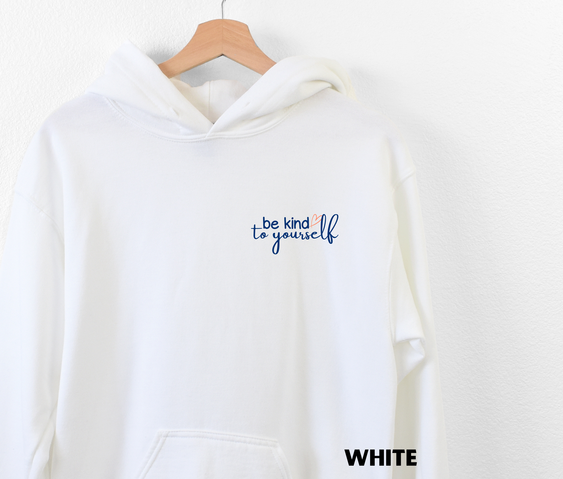 Embroidered Hoodie in white with "be kind to yourself' in navy blue text with a pink heart on the upper left chest. 