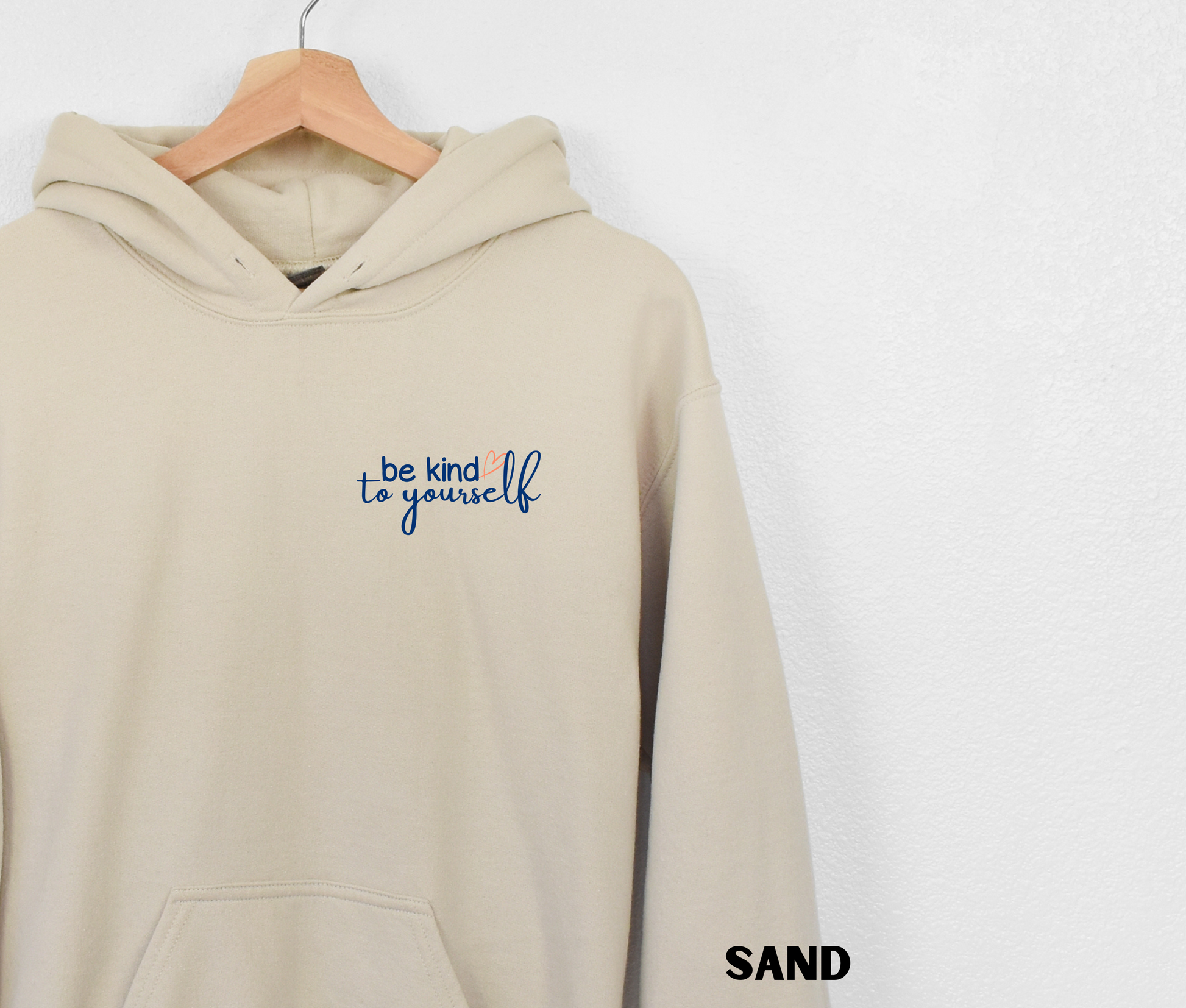 Embroidered Hoodie in a sand color with "be kind to yourself' in navy blue text with a pink heart on the upper left chest. 