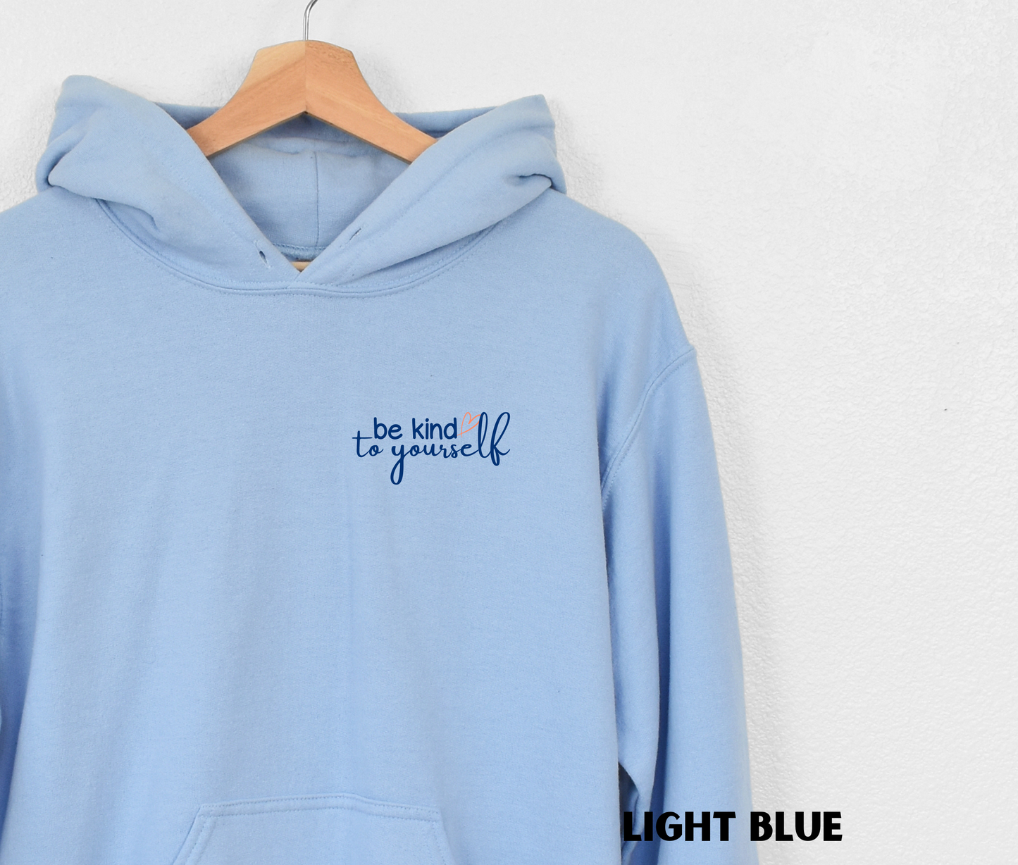 Embroidered Hoodie in light blue with "be kind to yourself' in navy blue text with a pink heart on the upper left chest. 