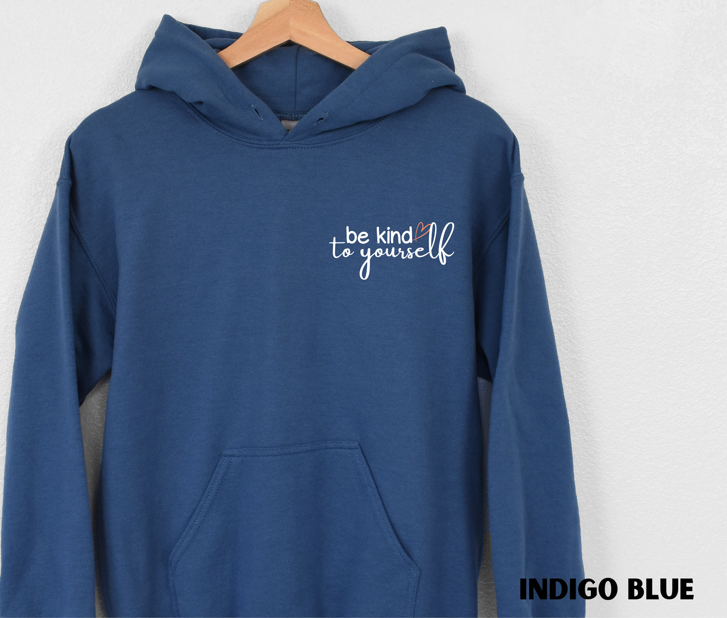 Embroidered Hoodie in indigo blue with "be kind to yourself' in white text with a pink heart on the upper left chest. 