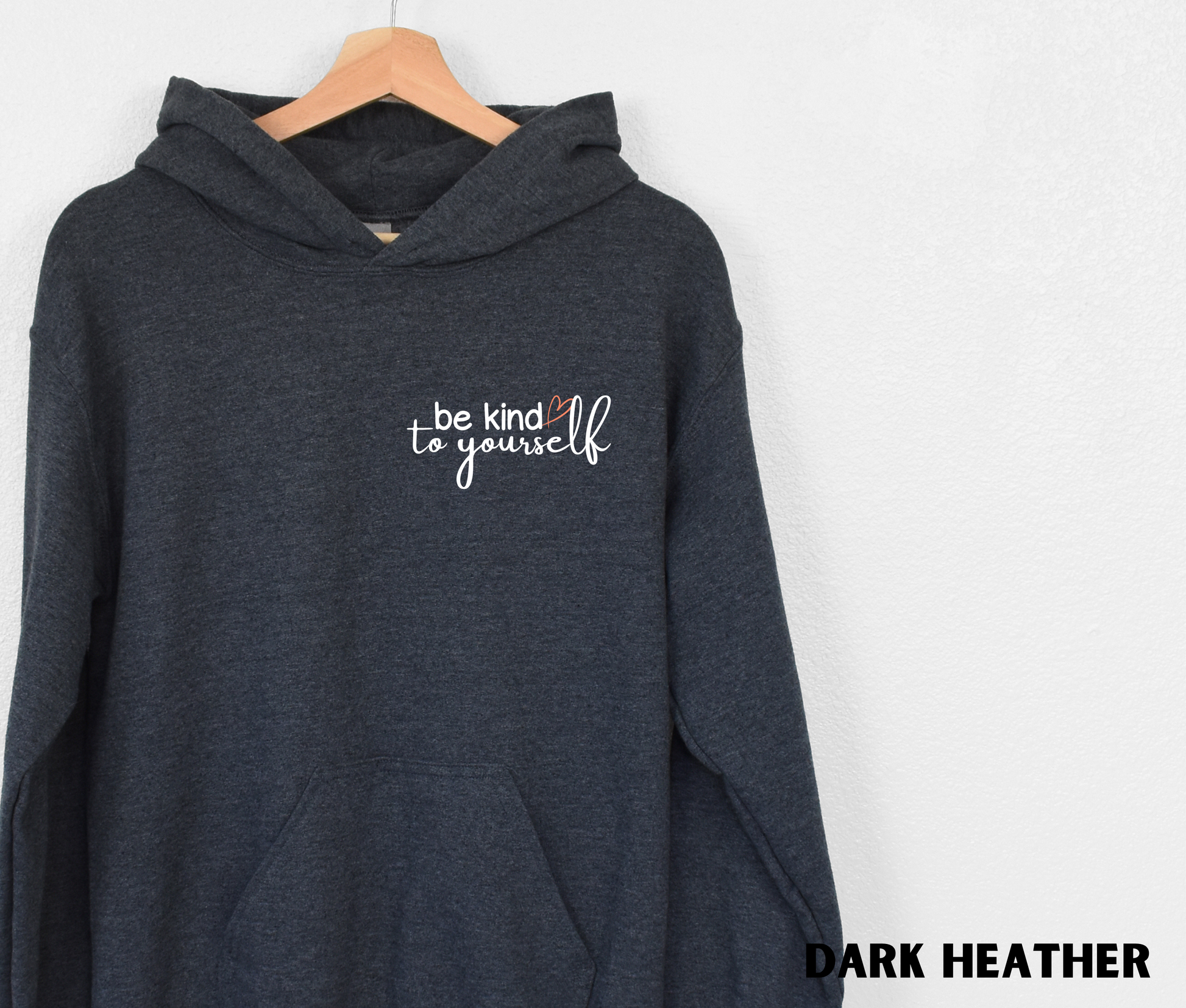 Embroidered Hoodie in dark heather with "be kind to yourself' in white text with a pink heart on the upper left chest. 