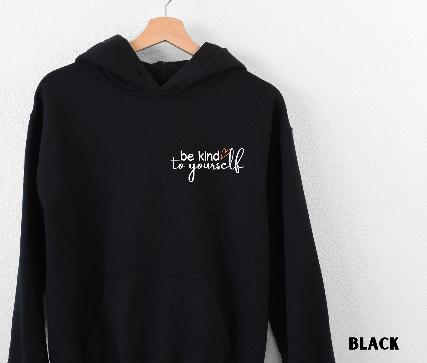 Embroidered Hoodie in black with "be kind to yourself' in white text with a pink heart on the upper left chest. 