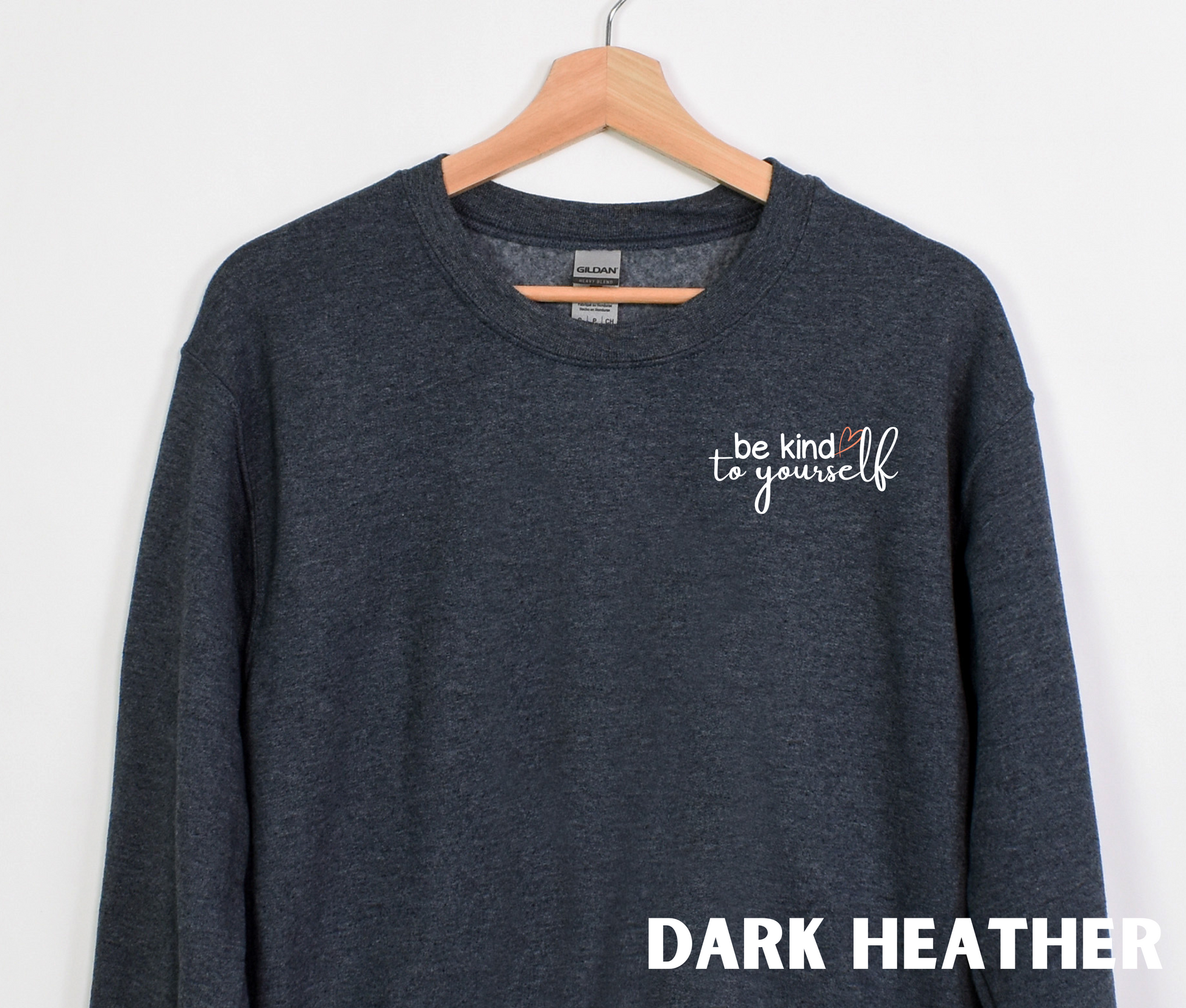 A dark heather embroidered crewneck sweatshirt with the words "be kind to yourself" embroidered in white with a pink heart on the left chest.