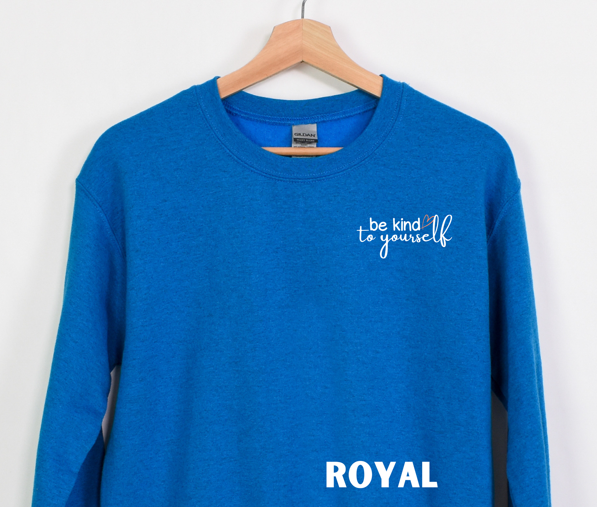 A royal blue embroidered crewneck sweatshirt with the words "be kind to yourself" embroidered in white with a pink heart on the left chest.